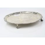 George V silver salver raised on four ball and claw feet, gadrooned border, makers Thomas Bradbury &