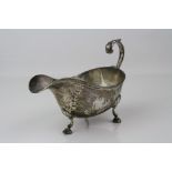 George V silver sauce boat raised on three hoof feet, shell shoulders, ribbed border, scroll handle