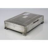 Silver rectangular cigar box raised on four stepped bracket feet, engine turned and banding