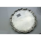 Edwardian silver salver of plain polished form with tiered ogee border and raised on three hoof