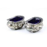 Pair of Edwardian silver open salt cellars, repoussé foliate scroll decoration to body, blue glass