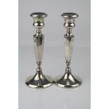 Pair of George V silver candlesticks, urn shaped sconce, faceted tapered stems to moulded circular