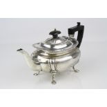 Early 20th century silver bachelor teapot raised on four hoof feet, gadrooning to rim, ebony