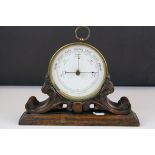 19th century Gilt Brass Cased Circular Aneroid Barometer held on a Scrolling Carved Wooden Stand,