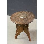 Indian Folding Table, the circular top with heavy floral carving and bone inlay, 45cms diameter x