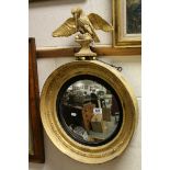 Regency Giltwood Convex Circular Wall Mirror surmounted by an Eagle holding a chain and balls in