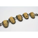 A silver panel bracelet with carved bone face decoration to each panel.