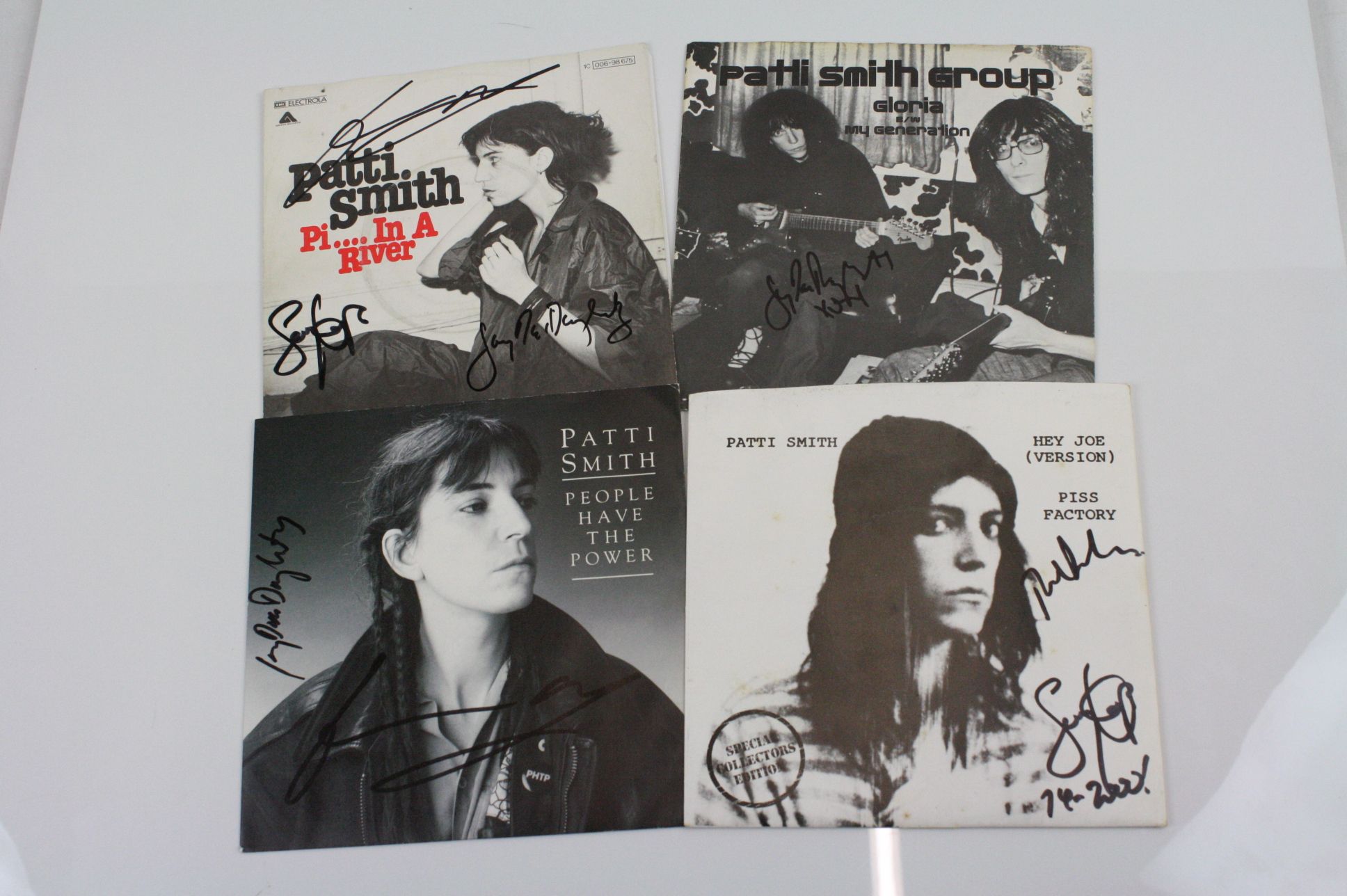 Music Autographs - Four signed Patti Smith 7" singles to include early German Piss In A River,