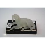 Moulded opaque glass figure of a dog on a black glass stand.