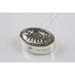 A silver pill box with decorative lid