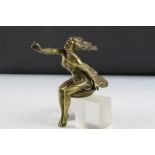 An early 20th century brass car mascot of a seated windswept lady.