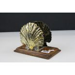 A novelty letter rack in the form of brass clam shells mounted on an oak plinth.