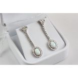 A pair of silver and CZ drop earrings set with opal panel