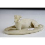 A carved alabaster sculpture of a recumbent greyhound.