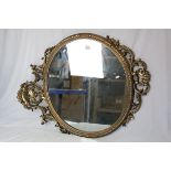 20th century Circular Mirror contained in an Ornate Gilt Frame, 107cms x 69cms