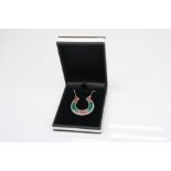 A silver horseshoe pendant necklace set with malachite and coral