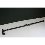 A wrought iron painted stick stand together with a quantity oif walking sticks.