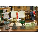 Three antique oil lamps with shades and chimneys together with two green glass shades with floral
