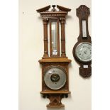 Antique oak carved Aneroid barometer and thermometer with reeded below a proscenium arch.