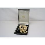 A pearl necklace with 9ct gold clasp together with a 935 silver brooch.