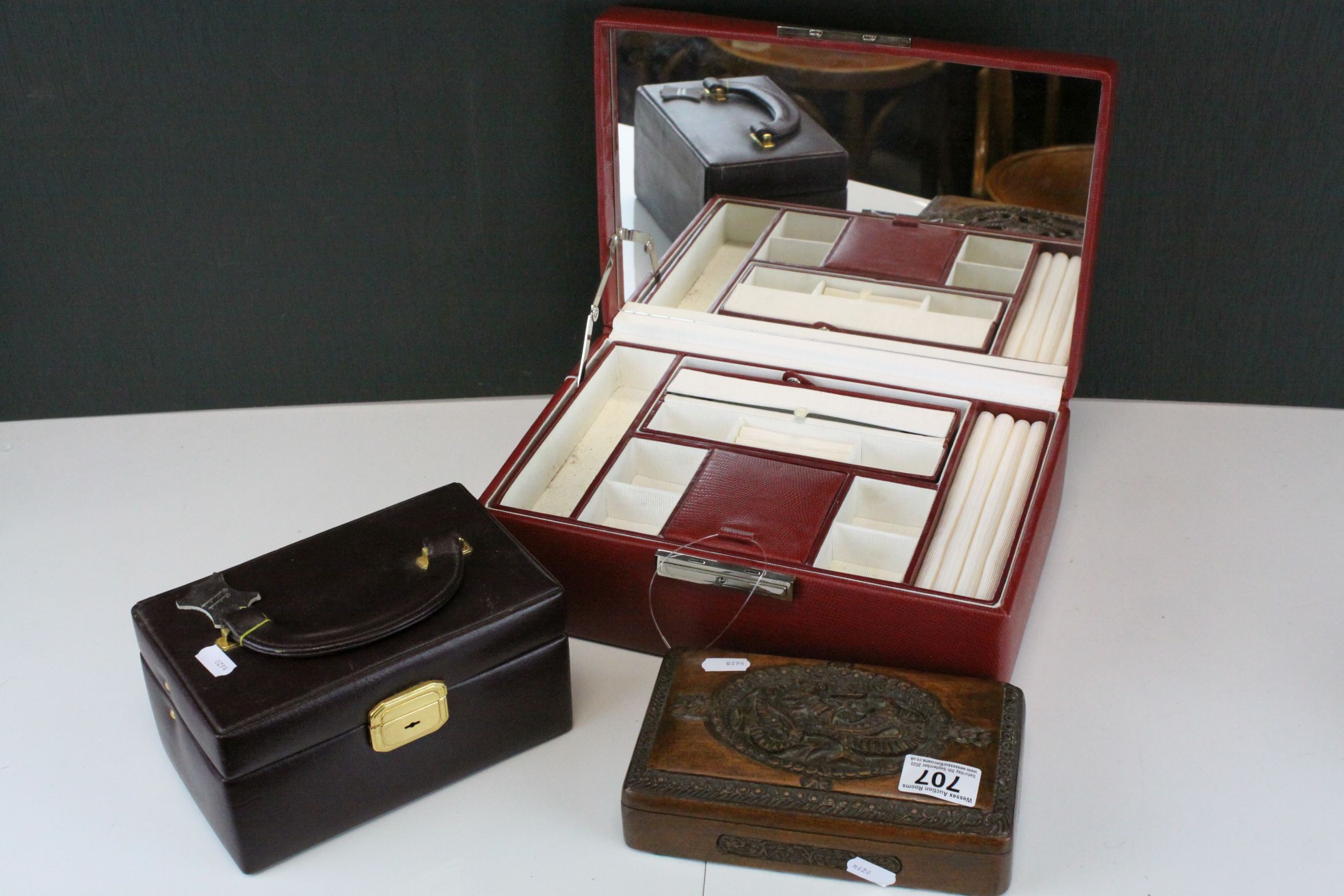 A red leather jewellery box with key, one other and a carved hardwood box.