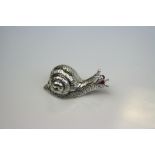 A silver figure of a snail with articulated shell
