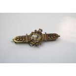 An Edwardian 15ct horseshoe and riding crop bar brooch.