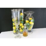 A group of glass vessels containing plastic lemons and limes