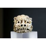 A IVORY NETSUKE OF A SHISHI HEAD IN THE MANNER OF TOMOTADA, Signed, well carved with a hinged