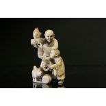A Meiji Japanese ivory group of father and son, signed, the father holding a fish aloft on a