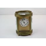 An oval brass cased carriage clock with white enamel dial, complete with key.