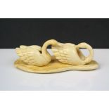 A late 19th century / early 20th century carved ivory ornament depicting a pair of swans on water.