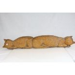 A large carved wooden Sculpture of two sleeping cats tail to tail.
