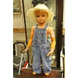A child mannequin dressed in dungarees and a straw hat.