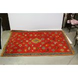 Wool Red Ground Rug decorated with stylised pattern including camels, other animals and birds,