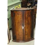 George III Oak Bow Fronted Hanging Corner Cupboard, the two doors opening to reveal shelves, 95cms