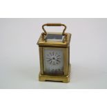 A miniature brass cased carriage clock with porcelain panels.