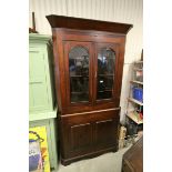 19th century Oak Corner Cupboard, the upper section with two glazed doors opening to reveal three