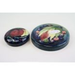 Two Moorcroft pot lids the largest measuring approx 8.5cm both marked Moorcroft to the underside.