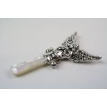 A silver babies rattle in the form of a guardian angel with mop handle