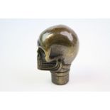 A brass/bronze walking stick handle in the form of a skull.