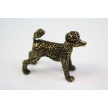 A brass figure of a poodle dog.