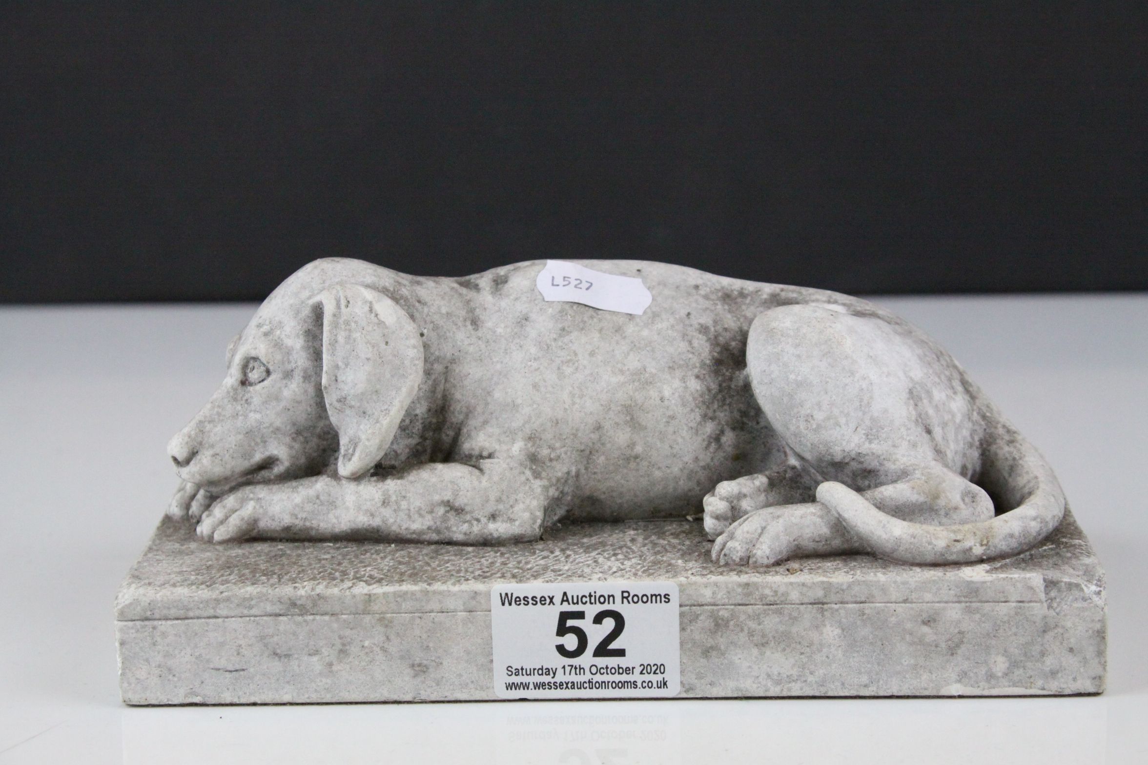 A stone effect scuplture of a recumbent dog.