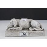 A stone effect scuplture of a recumbent dog.