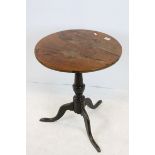 Early 19th century Elm and Oak Circular Tilt Top Table raised on a pedestal base with three swept