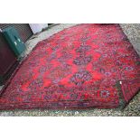 Large Wool Red Ground Rug with Stylised Pattern, label reading Park Dunedin, corners missing, 355cms