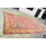 Large Wool Red and Yellow Ground Rug with stylised pattern, worn and with few holes, 450cms x
