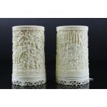 Pair of 19th century Chinese carved ivory cylindrical vases, each with figures in a landscape, on