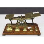 Set of Victorian brass postal scales with seven weights, raised on a mahogany base, 23cms wide