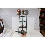 A set of graduating copper and metal saucepans together with a green painted pan stand.